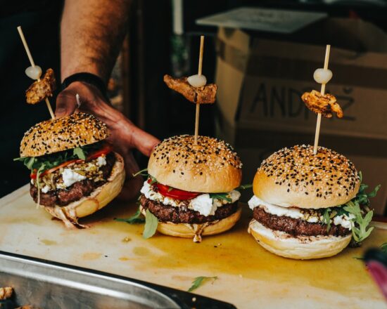 person som håller en hamburgare med köttbit och ost