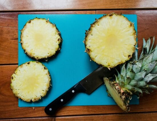 sliced pineapple fruit beside black handled knife